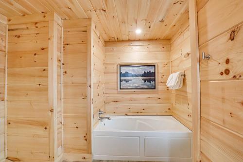 La salle de bains est pourvue d'une baignoire blanche et de murs en bois. dans l'établissement Misty Mountain Memories by Venture Smoky Mountains, à Gatlinburg