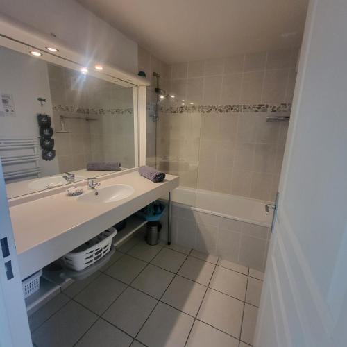 une salle de bain avec un lavabo, une baignoire et un miroir dans l'établissement L'ES-CALE DE BEG-MEIL AVEC PISCINE ET PLAGE Appartement avec 1 chambre et 1 alcôve, à Fouesnant