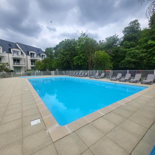 une grande piscine bleue entourée de chaises dans l'établissement L'ES-CALE DE BEG-MEIL AVEC PISCINE ET PLAGE Appartement avec 1 chambre et 1 alcôve, à Fouesnant