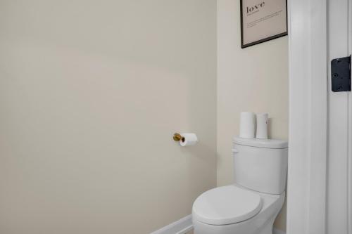 a white bathroom with a toilet and a roll of toilet paper at Luxury Niagara 3 Bdr Townhouse /Garage in Niagara Falls