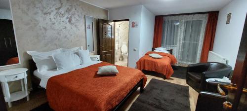 a hotel room with two beds and a chair at Pensiunea Montan in Durau