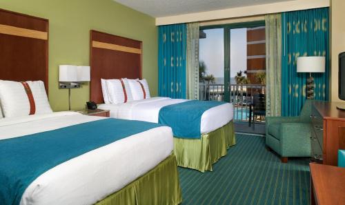 a hotel room with two beds and a balcony at Holiday Inn & Suites Virginia Beach - North Beach by IHG in Virginia Beach