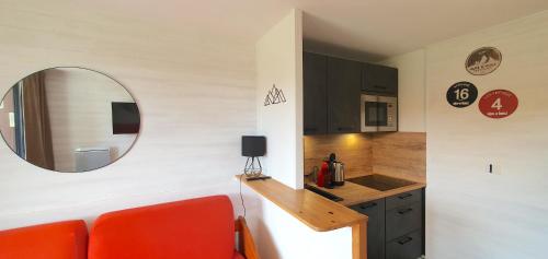 une cuisine avec un canapé rouge et un miroir dans l'établissement Pieds des pistes - Parking couvert - Plein sud, à L'Alpe-d'Huez