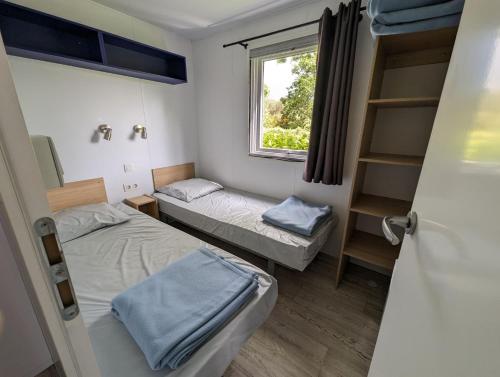 a small room with two beds and a window at Camping de Lanven in Plomeur