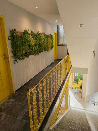 a stairway with a yellow rail and plants on a wall at HMG Rio Suítes in Rio de Janeiro