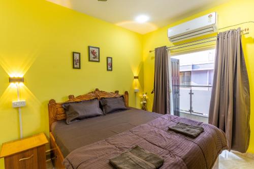 a bedroom with a large bed with yellow walls at 3BHK Villa - The Blue Pearl Varca Beach in Varca
