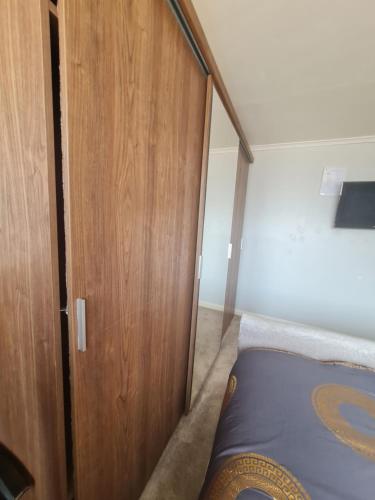 a bedroom with a wooden closet and a bed at The Rushdon in Grays Thurrock