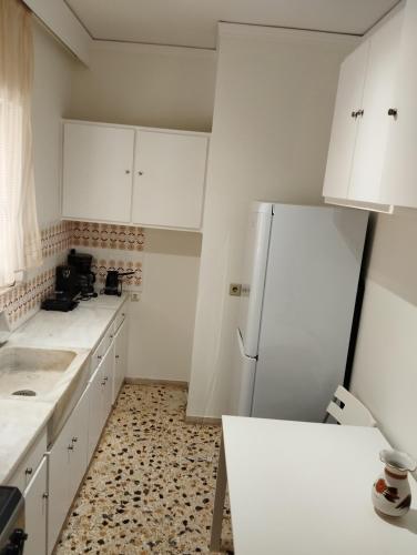 a kitchen with white cabinets and a refrigerator at Dim-Paul in Artemida