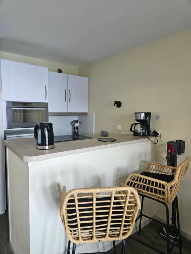 une cuisine avec un comptoir et deux chaises devant dans l'établissement Les pieds dans l'eau 4-6 personnes, à Douarnenez