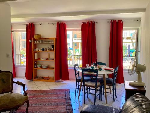 une salle à manger avec des rideaux rouges et une table avec des chaises dans l'établissement Appartment place d'équerre, à La Celle-sous-Gouzon