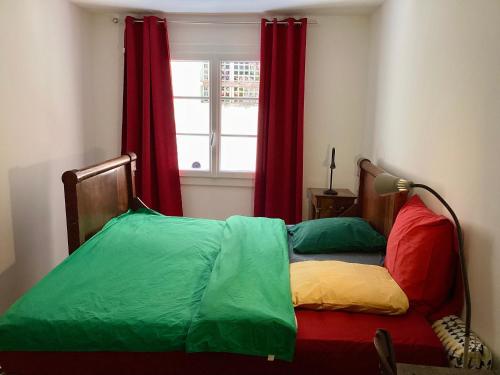 Ce lit se trouve dans un dortoir doté d'une fenêtre avec des rideaux rouges. dans l'établissement Appartment place d'équerre, à La Celle-sous-Gouzon