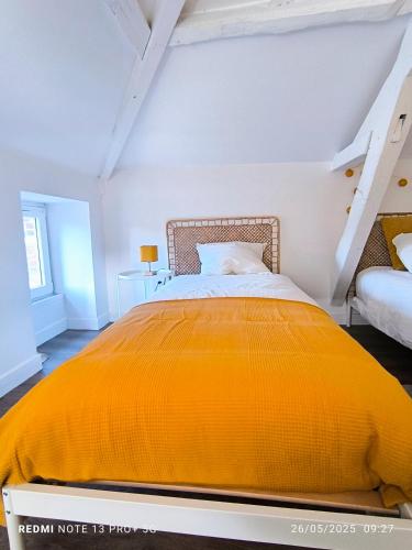 a bedroom with a bed with an orange blanket at Le Gîte des Capucines in Mauléon