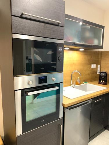 La cuisine est équipée d'un four en acier inoxydable et d'un évier. dans l'établissement Superbe T2 climatisé avec terrasse et jardin, à Arthès