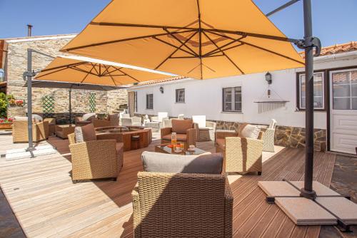 a patio with chairs and a large yellow umbrella at Quinta Penedo das Antas in Sertã