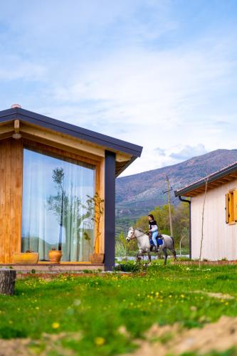 a person riding a horse in front of a house at Fishta Guesthouse - Mrizi i Zanave in Fishtë
