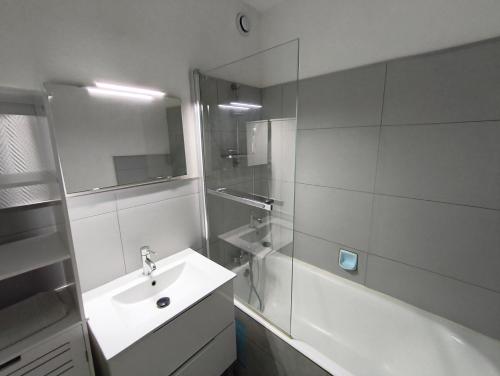 La salle de bains blanche est pourvue d'un lavabo et d'une baignoire. dans l'établissement Appartement à 5 min du port, à Vannes