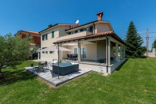a large house with a porch and a lawn at Apartment Vista Olivo in Brtonigla