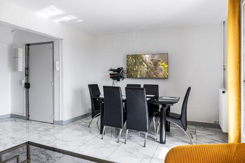 une salle à manger avec une table et des chaises noires dans l'établissement Spacieux et lumineux appartement refait à neuf, Bords de Marne et proche Paris, à Neuilly-sur-Marne