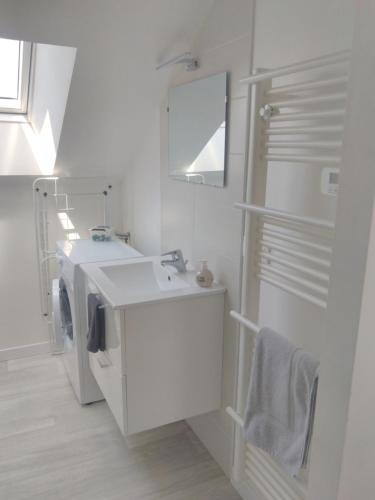une salle de bain blanche avec un lavabo et un miroir dans l'établissement T2 centreville, appart lumineux,1 chambre, 4 pers, climatisation, wifi, parking gratuit, à Lorient