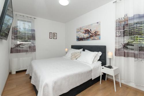 a white bedroom with a bed and a table at Villa Jolanda in Plano