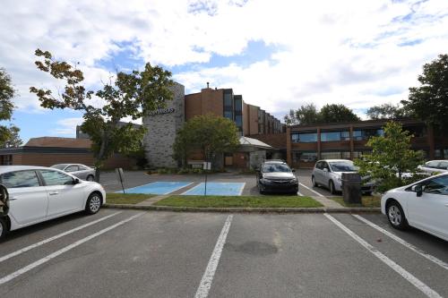 un parking avec des voitures garées devant un bâtiment dans l'établissement Hôtels Gouverneur Rimouski, à Rimouski