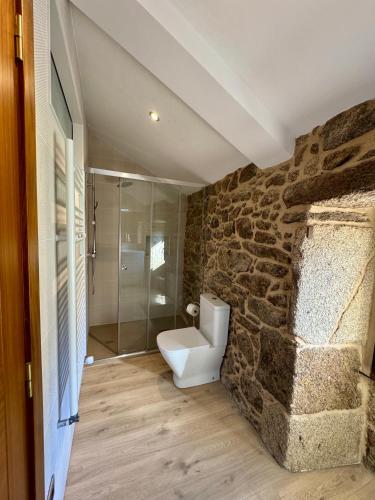 a bathroom with a toilet and a stone wall at Mar do Val in Muxia