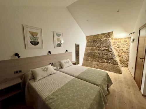 a bedroom with two beds and a stone wall at Mar do Val in Muxia