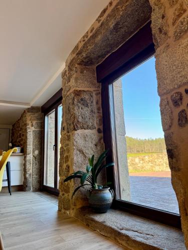 a stone walled room with a window and a plant at Mar do Val in Muxia
