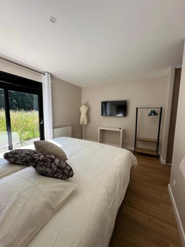 une chambre avec un lit blanc avec deux oreillers dessus dans l'établissement Chez Babeth Maison atypique en conteneurs pour 10 personnes, à Sizun