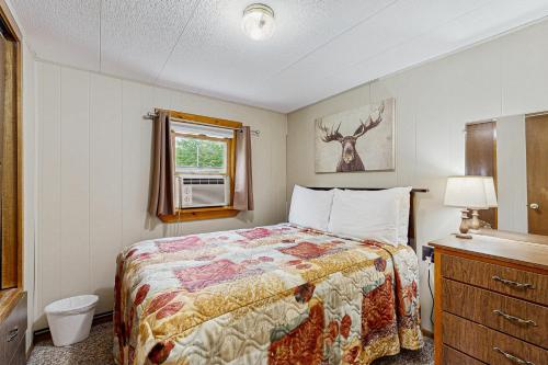 a small bedroom with a bed and a window at Riverbank's Pemi Cottage in Lincoln