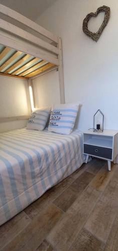 - un lit avec deux oreillers et un cœur sur le mur dans l'établissement Charmant T2 avec loggia belle vue mer et parking, à Saint Pierre La Mer