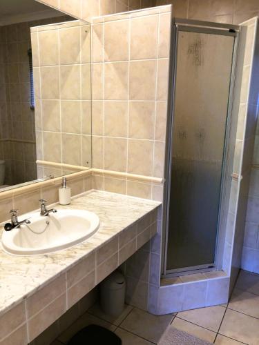 a bathroom with a sink and a shower at Villa Arroyo, Estuary Estate, Port Edward in Port Edward