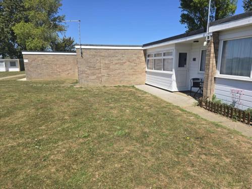 a house with a lawn in front of it at 115 Modern South Facing Chalet on Sunbeach in Scratby Near Great Yarmouth in Scratby