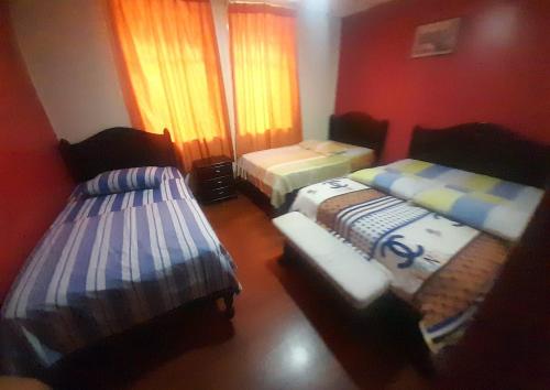 two beds in a room with red walls at HOSTAL CALIFORNIA in Quito