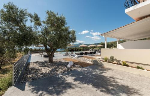 a patio with a tree and benches and a building at Marea Luxury Suites in Koríthion