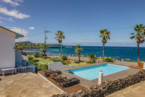 a swimming pool with a view of the ocean at Le Village Aewol G in Jeju