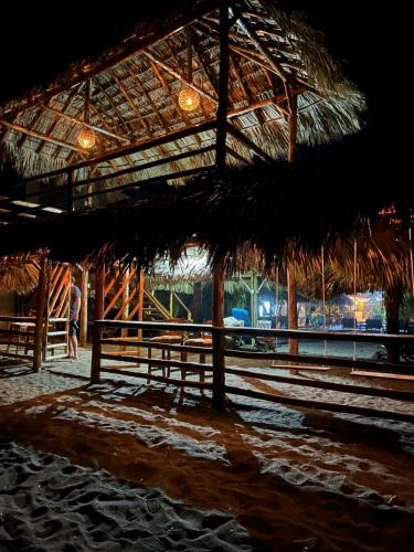 a straw hut with a table and benches on the beach at Hotel Tranquilo in Las Peñitas