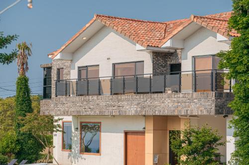 a house with a balcony on top of it at Le Village Aewol building A in Jeju