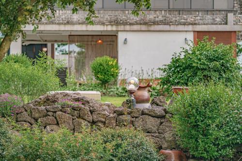 a stone wall in front of a house with a vase at Le Village Aewol building A in Jeju