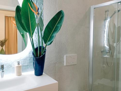 a blue vase with a plant on a bathroom counter at Santa Cruz - B&B in Lagos