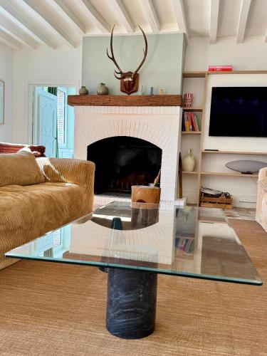a living room with a glass table in front of a fireplace at Magnifique longère proche Dreux et à 1h de Paris in Muzy