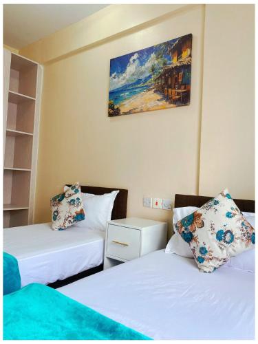a room with two beds and a painting on the wall at Ntates Place Mombasa in Mombasa