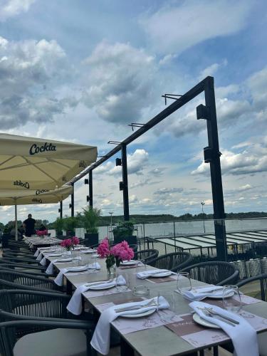 a row of tables with white plates and flowers on them at Belvedere RESORT in Smederevo