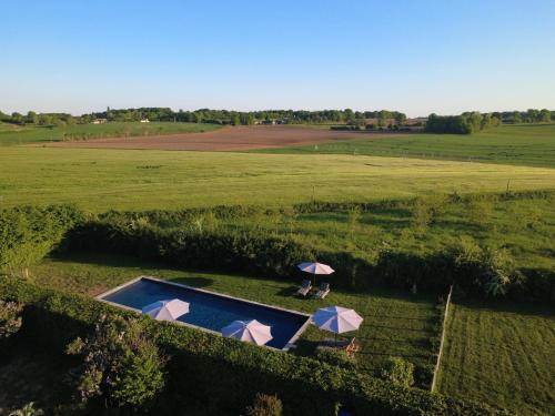 an overhead view of a field with a pool and two umbrellas at Maison de vacances avec piscine chauffée, jacuzzi et jardin privé - proche circuit des 24h du Mans in Saint-Christophe-en-Champagne