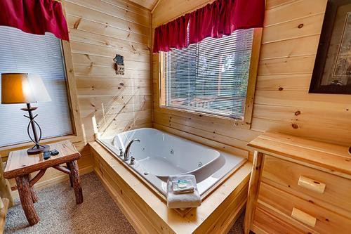 une salle de bain avec une baignoire, une table et une lampe dans l'établissement The Bear Crossing by Venture Smoky Mountains, à Pigeon Forge