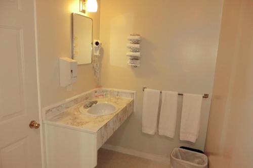a bathroom with a sink and a mirror and towels at Admiral Digby Inn Restaurant and Cottages in Digby