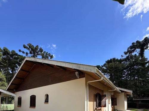 a large white building with trees in the background at Pequeno Paraiso in Campos do Jordão