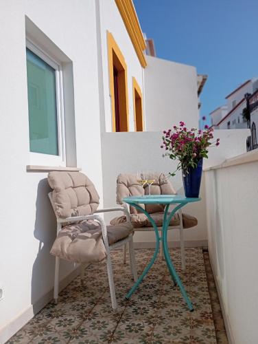 a table and a chair on a balcony with flowers at Santa Cruz - B&B in Lagos
