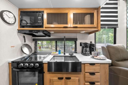 a small kitchen with a stove and a microwave at Glamping at KY Lake 1 min from Carper Cove in Springville