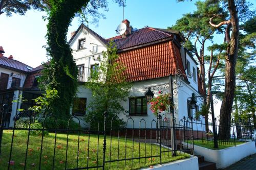 a white house with an orange roof and a fence at Willa Victor in Jastrzębia Góra